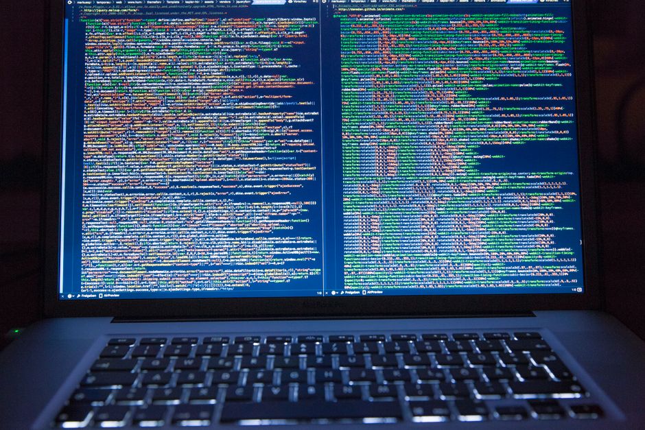 Laptop displaying source code with dual screens for software development.
